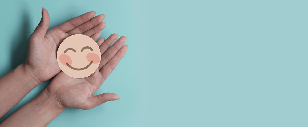 Hands holding smiley face made of cardboard